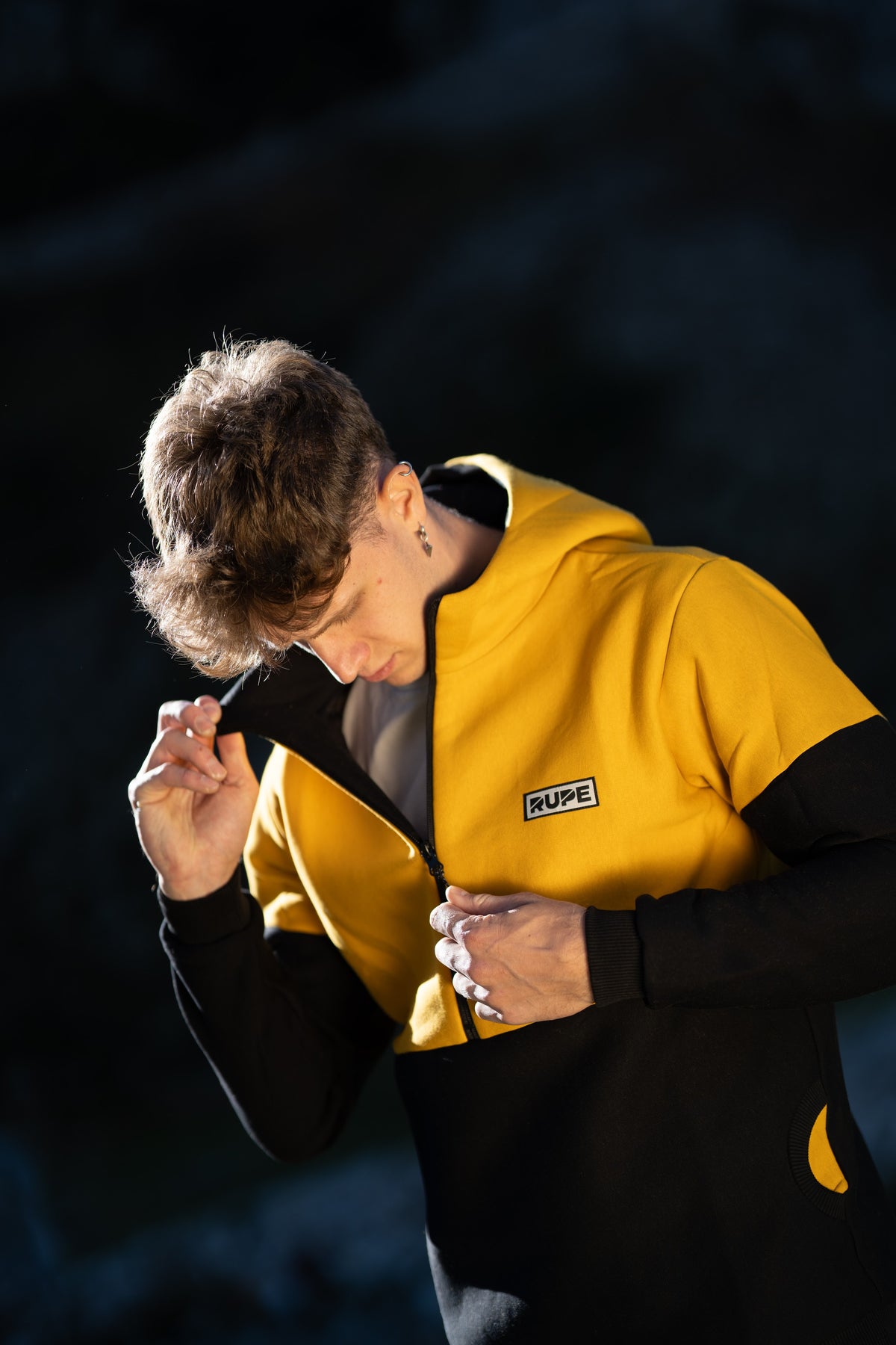 FW26-113 Pitch Bee (dettaglio zip e cappuccio, uomo che apre la zip)