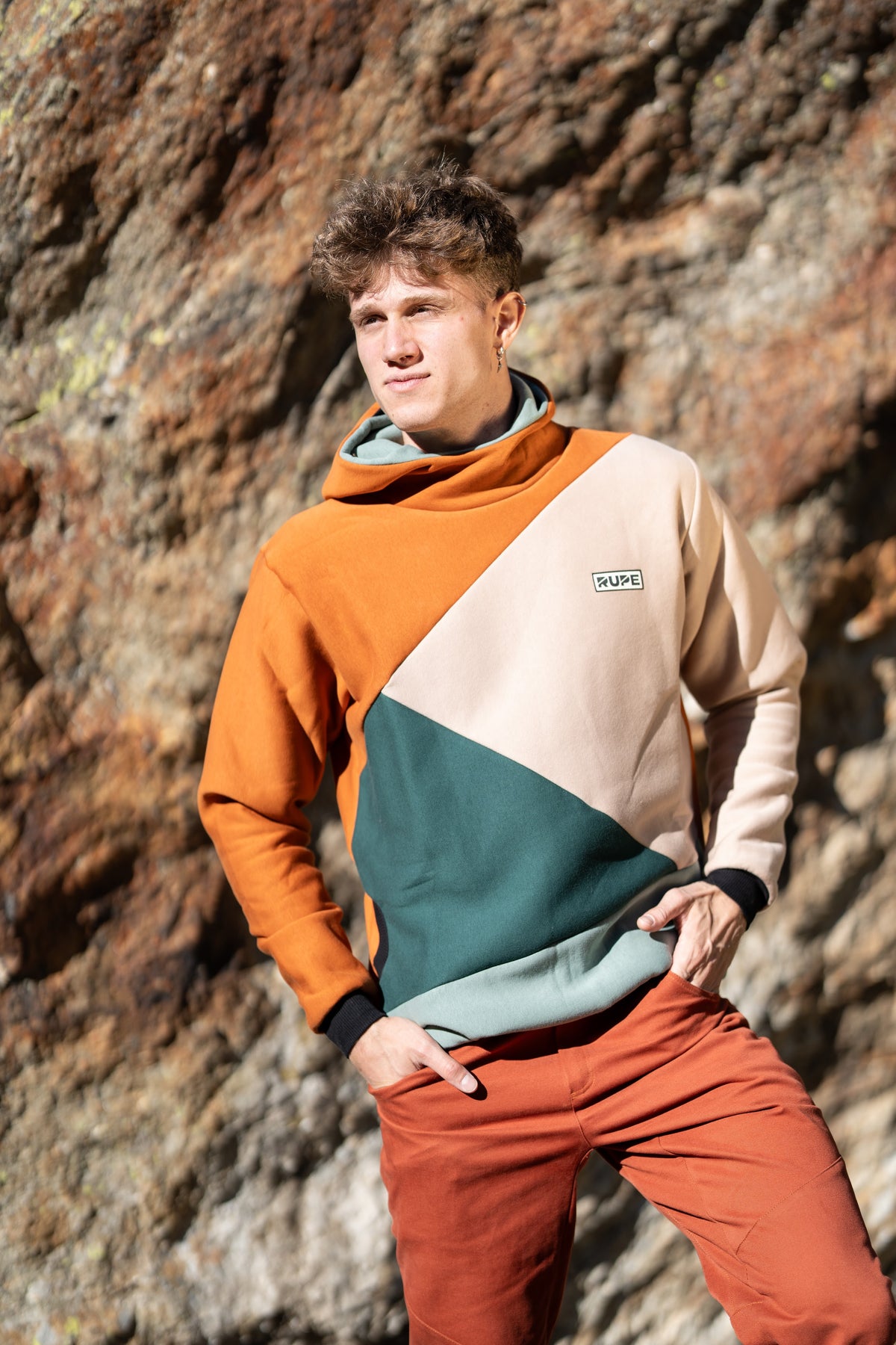 FW26-124 BLOCK Foxe + Pirenei Rust (uomo appoggiato alla roccia, profilo)