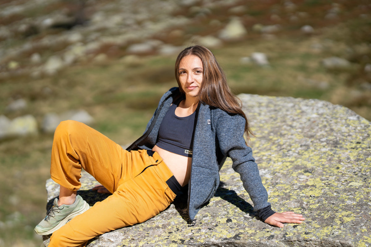 FW26-080 Peak Asfalt + Core Navy + Ande Ocra (orizzontale, donna sdraiata sul masso)