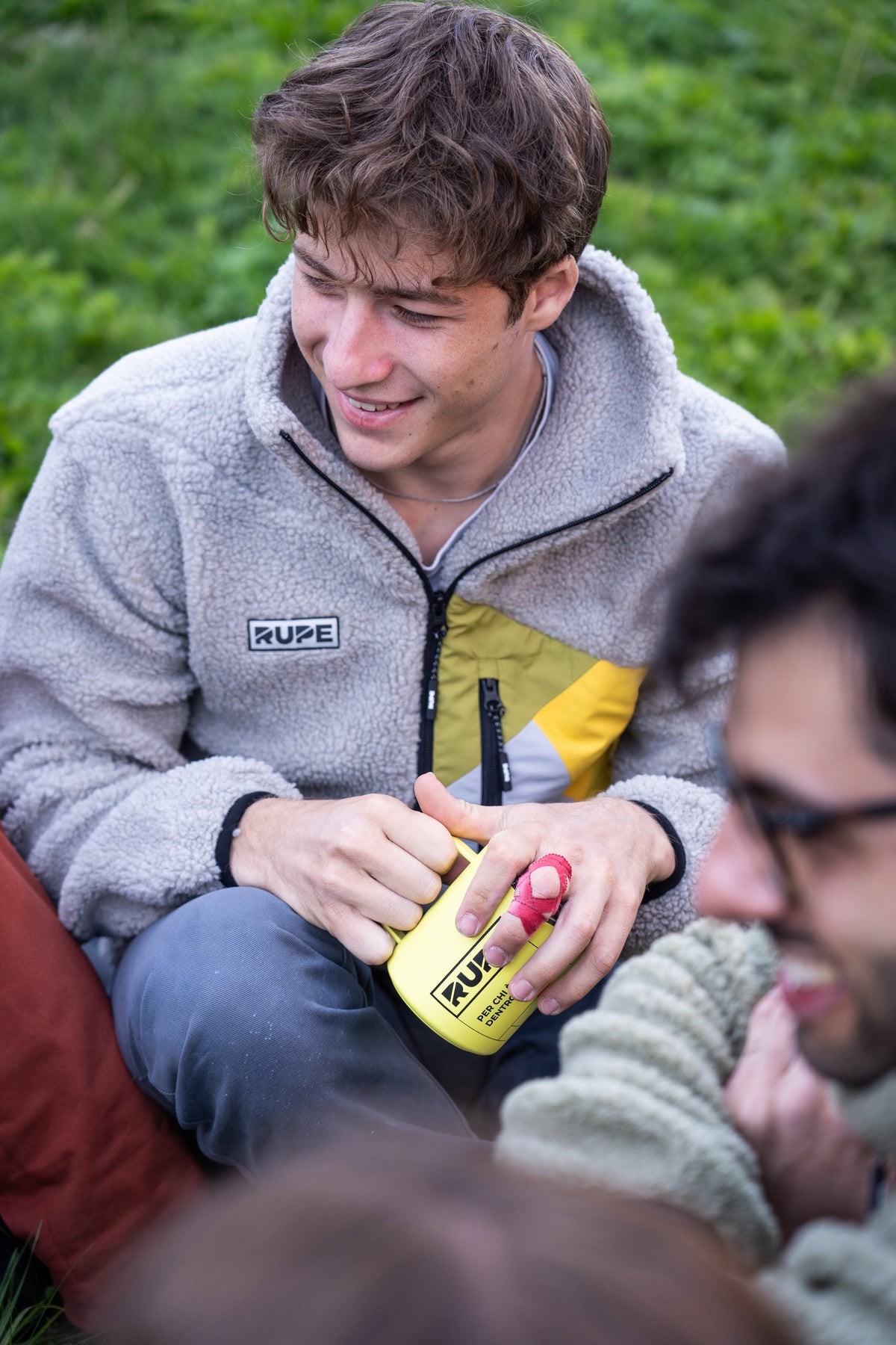 FW26-048 Yeti 2.0 Sunny + Himalaya Grey (uomo sorridente con tazza Rupe gialla, campo)